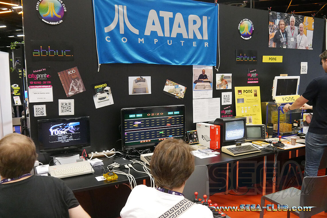 Große blaue ATARI Computer Flagge hängt am Stand mit mehreren Home Computer Systemen und dem Spiel Pong