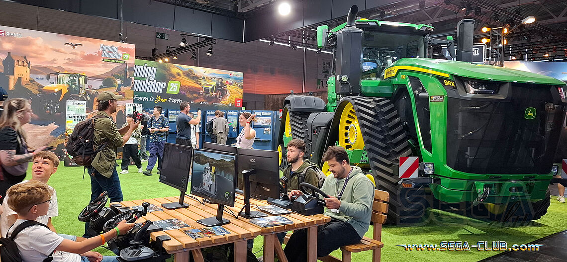 Farming Simulator 25 am Holztisch, im Hintergrund ein riesiger grüner Traktor