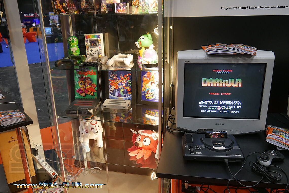 Mega Drive mit dem Spiel Darkula (mit k) - tatsächlich korrekt geschrieben und nicht Drakula. Daneben eine Vitrine mit Games wie Banjo-Kazooie und Plüschis