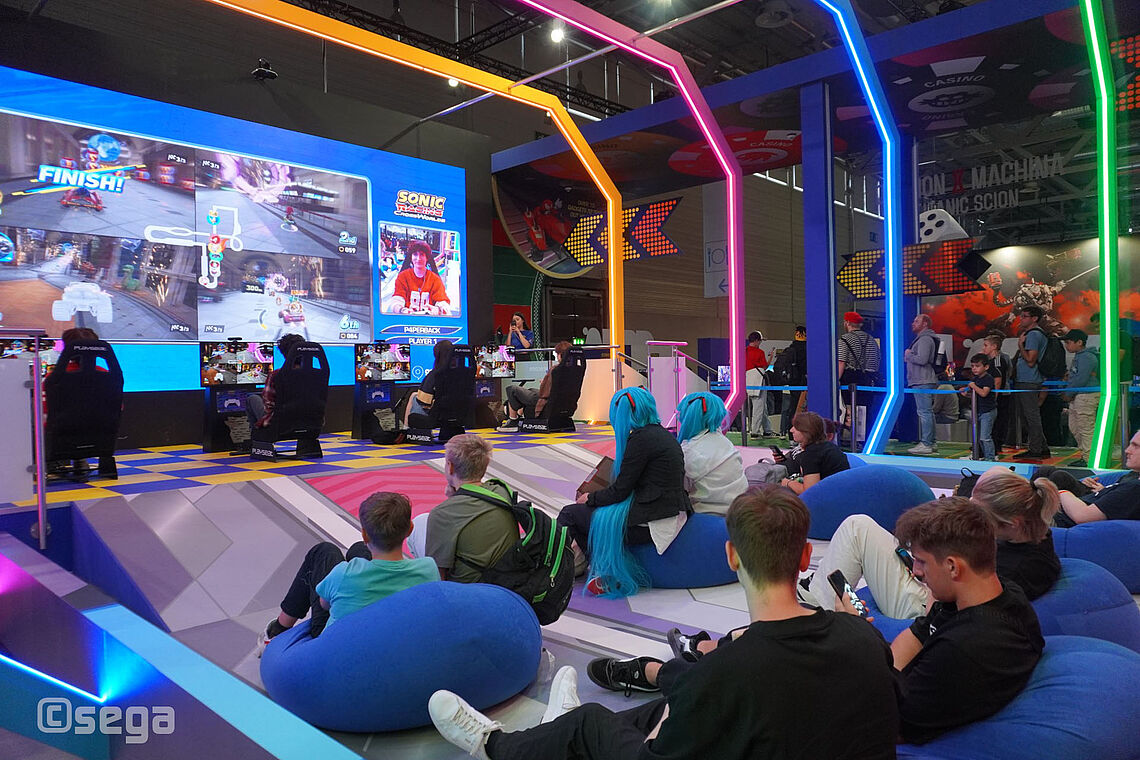 Blick von den Spielern auf den Sitzkissen hin zum Großbildschirm auf der Bühne