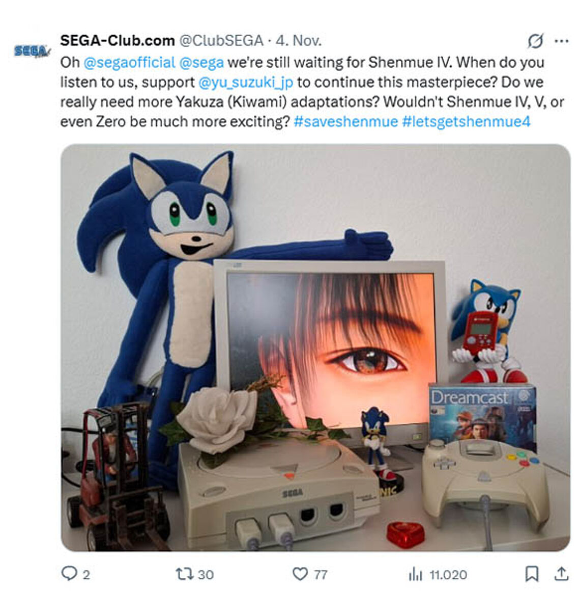 Shenhue Artwork ihres Auges aus dem Shenmue Passport zusammen mit Dreamcast Konsole und Sonic-Merchandise